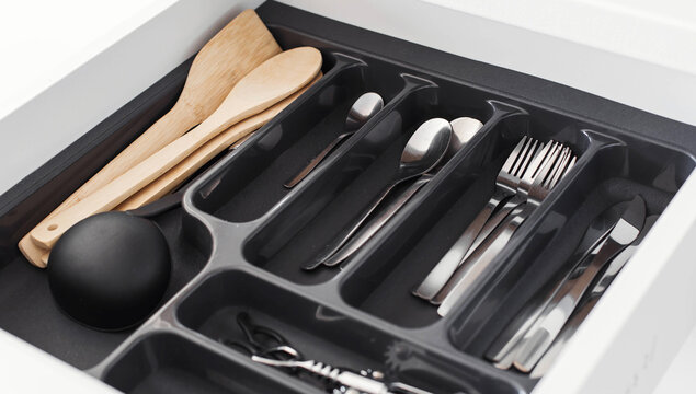 Close up of stainless steel spoons and forks stored in kitchen drawer organizer modern home organization cleanliness and everyday cooking concept