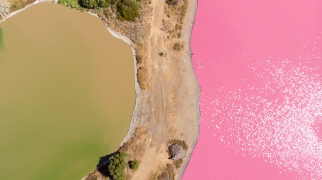 Aerial view of the striking contrast between the green and pink waters of two adjacent lakes, divided by a narrow strip of land, Port Melbourne, Victoria, Australia.