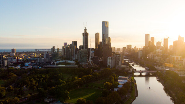 Aerial view of Melbourne's skyline bathed in the warm glow of the setting sun, Yarra River reflecting the light, Melbourne, Victoria, Australia.