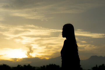Fototapeta premium Silhouette of an Asian woman at sunset. Illustration of a lonely woman, an introverted woman. World Introvert Day.