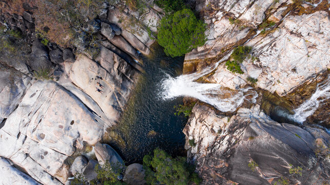 Aerial view of Emerald Falls cascading over rocky ledges into a serene pool below, framed by verdant trees, Emerald Falls, Queensland, Australia.