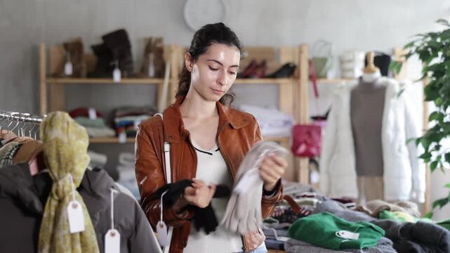 Armenian woman near showcase examine goods, buying gloves. Off line clothing store from retailer. Style and fashion type look, modern trends. Designer clothing store, vintage fashion, limited edition