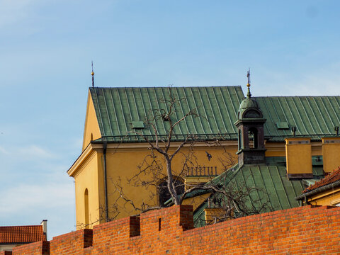 Green spire of a church contrasting with the yellow-orange historic building and red brick city walls. - Powered by Adobe
