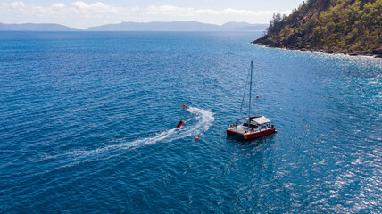Aerial view of a boat floating on the blue sea water near the Whitsunday Islands, Whitsundays, Queensland, Australia.
