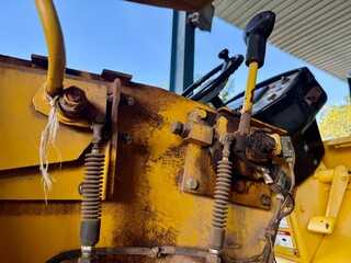 Close-up of worn control levers and hydraulic components on heavy machinery. Industrial equipment detail showing mechanical wear, maintenance conditions, and construction machine operation.