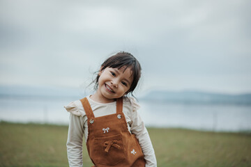 happy toddle girl smilling on grass field near the river