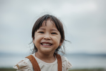 happy toddle girl smilling on grass field near the river