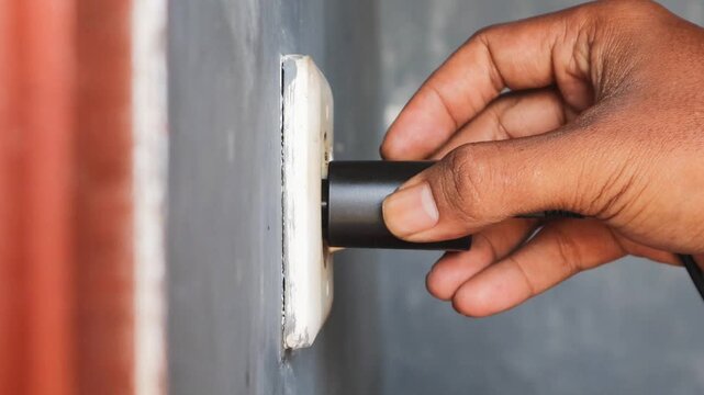 Man's hand view plugging a mobile phone charger cable into a wall socket. Ready to connect, plug in electricity