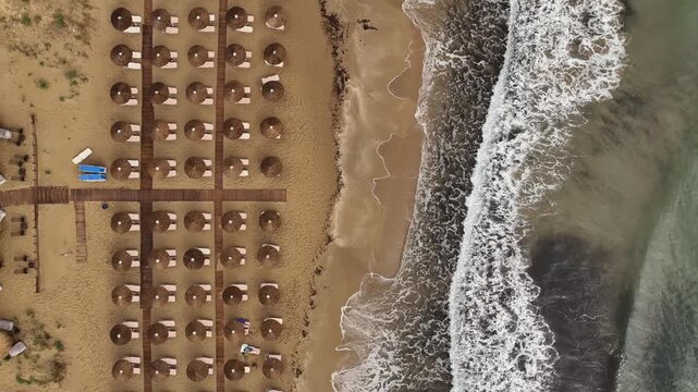 Aerial view of beach umbrellas lining the sandy shore where the turquoise sea meets the coast, creating a stunning contrast of colors, Korission, Corfu, Greece.