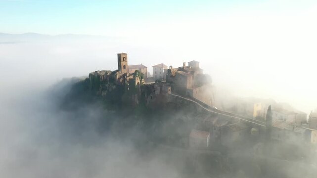 Aerial view of Celleno, a medieval village perched atop a hill, shrouded in ethereal mist, creating a striking contrast between the ancient architecture, Celleno, Lazio, Italy.
