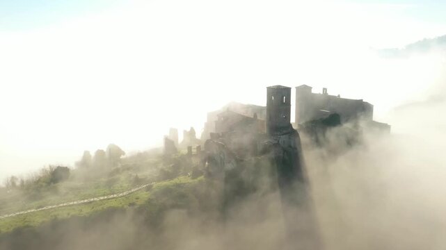 Aerial view of the ancient ruins of Celleno shrouded in a mystical fog, creating a hauntingly beautiful scene with contrasting textures, Celleno, Lazio, Italy.