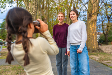 Obraz premium Young girl photographer taking pictures of smiling sisters