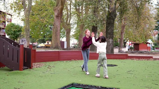 Two young friends joyfully perform a synchronized cartwheel in an outdoor playground, celebrating with a high five at the end, showcasing their friendship, energy, and gymnastic skill