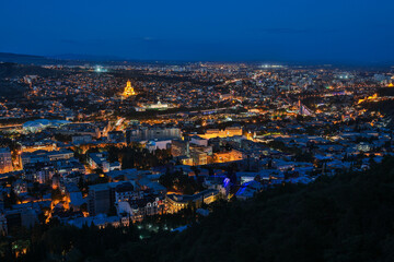 Fototapeta premium Panoramic Night View of Illuminated Tbilisi Cityscape and Sameba Cathedral