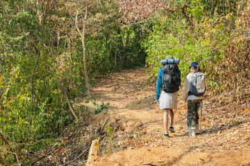 Fototapeta premium Travel young couple hike walk autumn forest mountain nature trail, people exploring with backpacks, enjoying peaceful outdoor journey, discovery seasonal beauty