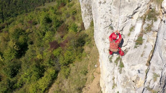  Flying near a mountain rescuer rappelling on a rocky wall with a drone