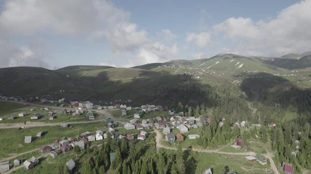 Aerial drone view of Gomis Mta, a mountain village in Georgia, featuring small wooden houses surrounded by patches of snow and green hills