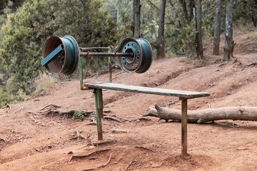 Makeshift gym equipment in an outdoor setting, featuring a homemade bench press with weights made...