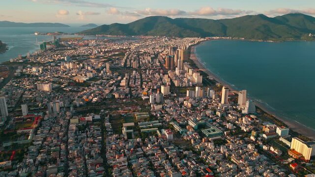 sunny sunset in Vietnamese coastal Da Nang city, My Khe sand beach and touristic My An and Son Tra district with modern skyscraper hotels and resorts, blue sea of Danang, Vietnam, aerial drone view 4k