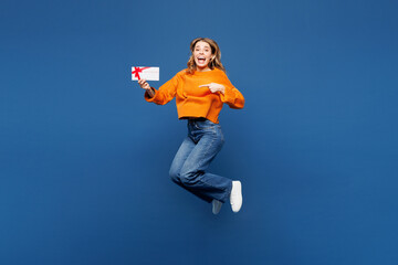 Obraz premium Full body young happy Caucasian woman she wear yellow sweater casual clothes jump high hold point on gift certificate coupon voucher card for store isolated on plain blue background Lifestyle concept