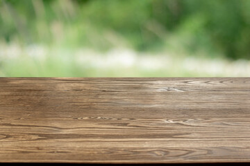 Wooden table surface with blurred green natural background for product placement