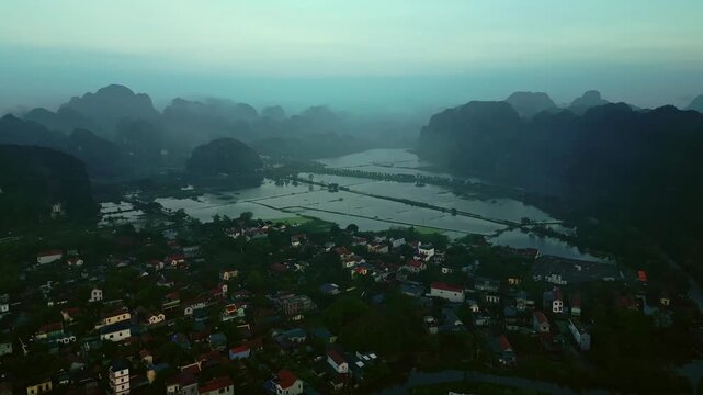 Aerial view of the scenic landscape of Hoa Lu featuring limestone karsts, rice paddies, and a village nestled amongst the greenery, Hoa Lu, Ninh Binh, Vietnam.