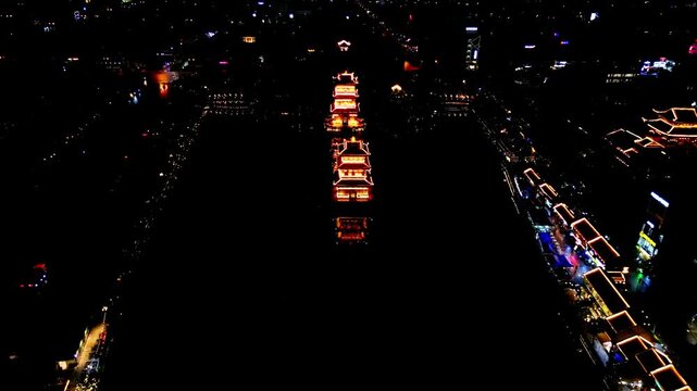 Aerial view of illuminated pagodas and buildings stand out against the dark water and night sky, creating a stark contrast of light and shadow, Hoa Lu, Ninh Binh, Vietnam.