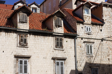 A view of rusty railway tracks in Split, Croatia, leading toward the city center with a historic church tower and a large mountain backdrop. © Impresyjna