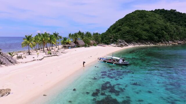 Aerial view of the boat anchored on the pristine white sands of Gigantes Islands framed by lush green trees and clear turquoise waters, Carles, Western Visayas, Philippines.