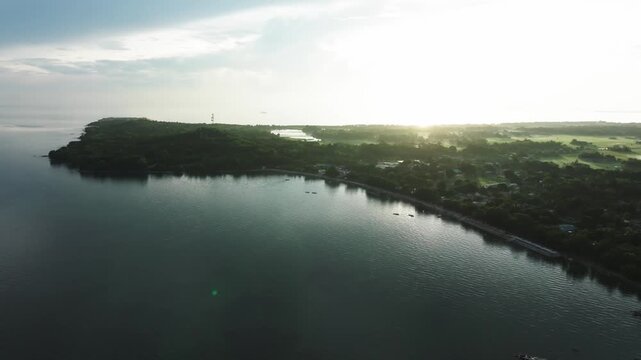 Aerial view of the tranquil coastline, where the dark ocean meets the lush green vegetation, creating a striking contrast along the shore, Carles, Western Visayas, Philippines.