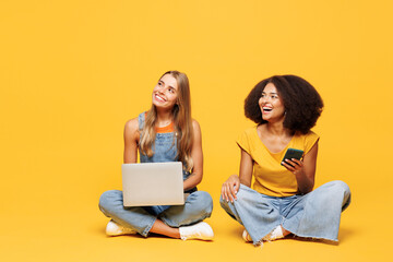 Full body two young friends buddies IT women wear denim casual clothes sit together hold work on...