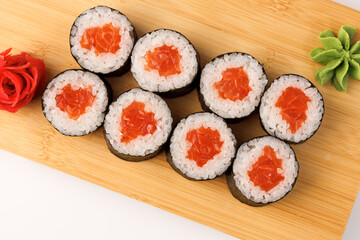 Delicious sushi rolls arranged on a wooden board with garnishes