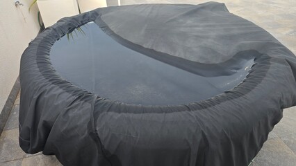 Jacuzzi on a balcony covered with protective foil and water on the cover
