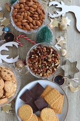 Various Christmas decorations, cookies, chocolate and nuts on wooden background. Flat lay.