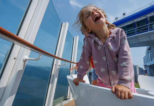 Girl with a big smile is leaning over on ferry crossing channel
