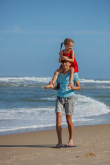 Joyful children playing piggyback ride together by the seaside