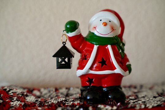 A Santa-style snowman toy holds a lamp