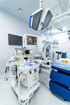 Surgical theater with C-arm and anesthesia station. Interior of a fully equipped surgical room featuring an anesthesia workstation,  fluoroscopy machine, and operating table ready for a procedure.
