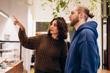 Young man and woman choosing menu in cafe, woman pointing at menu board.
