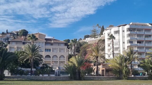 Sunny panish residential street with palm trees, mountains, on blue sky background