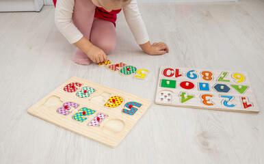 little girl playing with a wooden educational number puzzle toy