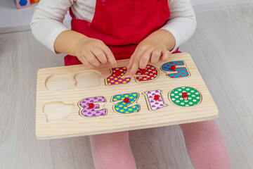 little girl playing with a wooden educational number puzzle toy