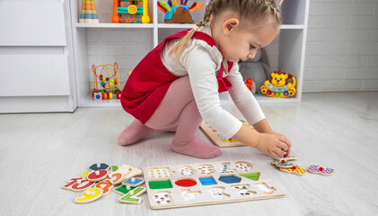 Fototapeta premium little girl playing with a wooden educational number puzzle toy