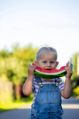 Happy little girl eating a piece of juicy watermelon.