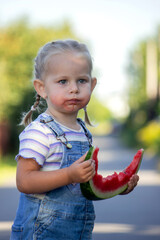 Happy little girl eating a piece of juicy watermelon.