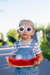 Happy little girl eating a piece of juicy watermelon.