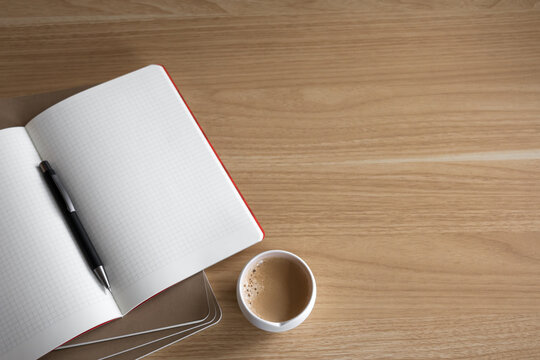 modern wooden desk setup from above with blank notebook ready for notes, a pen, and coffee. minimalist desktop with copy