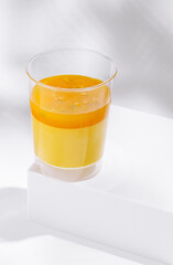 Bright yellow and orange layered pudding served in clear cup on white pedestal