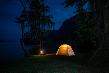 Night camping adventure with a cozy tent lit under the starry sky in a summer forest
