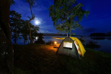 Night camping adventure with a cozy tent lit under the starry sky in a summer forest
